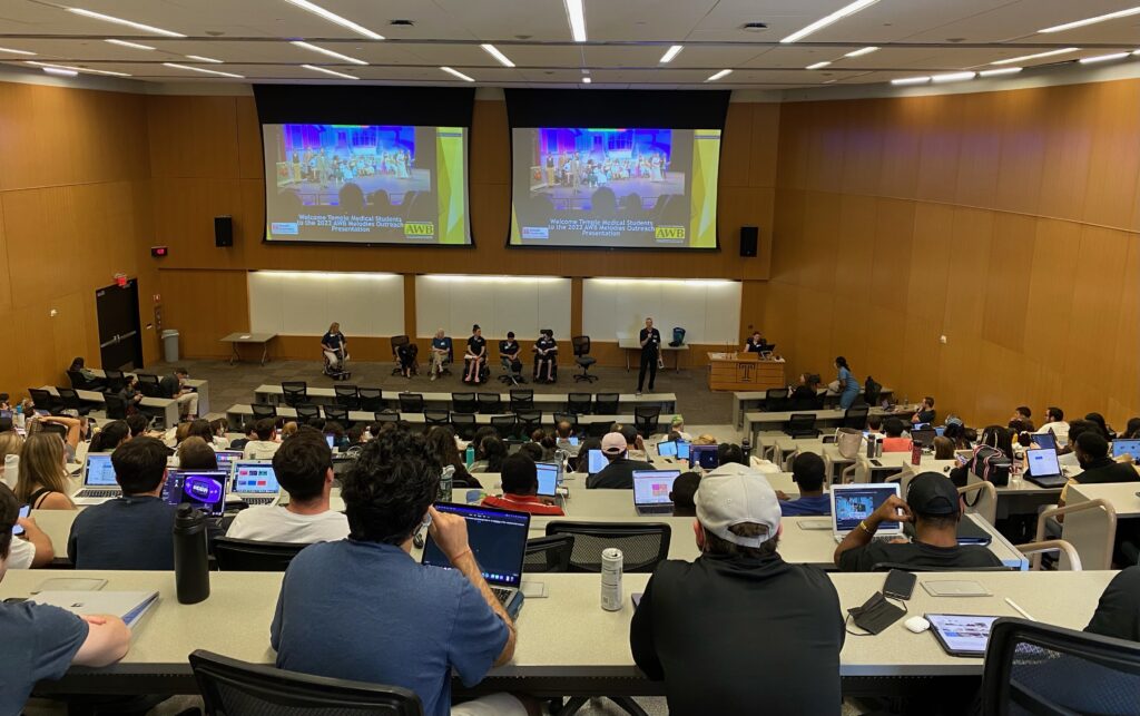 Students in a large classroom listening to a presentation by AWB members